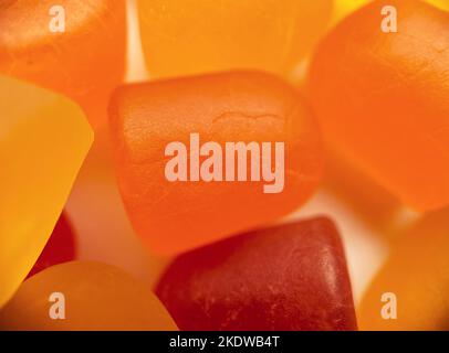 Gros plan de la texture des gommies multivitaminées orange et jaune sur fond blanc. Concept de mode de vie sain Banque D'Images