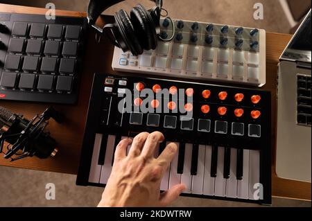 La main du musicien sur le clavier midi, les écouteurs de studio. Lieu de travail d'un musicien, compositeur, ingénieur du son. Studio d'enregistrement professionnel, Stud pour la musique à domicile Banque D'Images