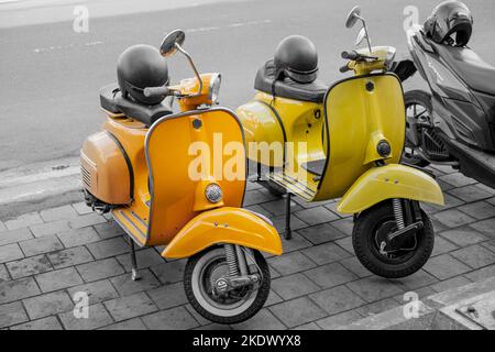 Scooter jaune et orange vintage tandis que les autres objets sont monochromes ou noir et blanc ou désaturés Banque D'Images