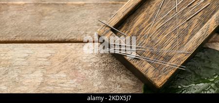 Planche avec aiguilles d'acupuncture sur fond en bois avec espace pour le texte, vue de dessus Banque D'Images