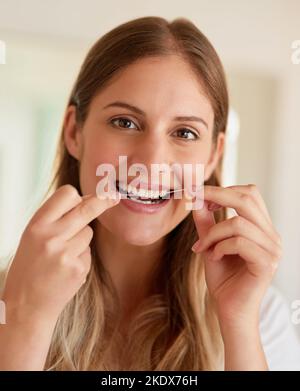 Il commence par des habitudes saines. Portrait d'une jeune femme qui chante ses dents à la maison. Banque D'Images