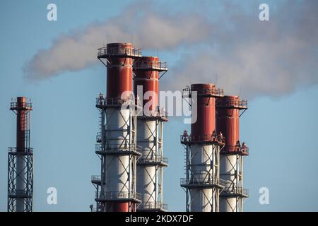 Les cheminées en métal rouge et blanc fument sont sous le ciel bleu pendant la journée. Équipement de centrale électrique Banque D'Images