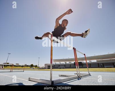 Course à pied, saut et haies d'athlète pour un exercice de vitesse, un marathon ou un entraînement de coureur dans un stade. La santé, le cardio et l'homme court courir rapidement pour un saut Banque D'Images