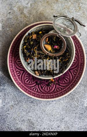 De dessus les feuilles de thé vert sencha avec des morceaux de mangue sur fond de béton Banque D'Images