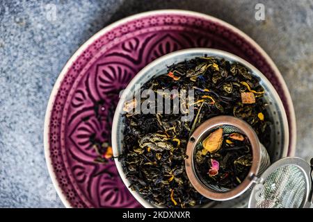 De dessus les feuilles de thé vert sencha avec des morceaux de mangue sur fond de béton Banque D'Images