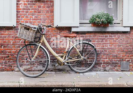 Vélo d'époque avec panier en osier garé près du bâtiment en brique rouge de la maison près de la fenêtre en Belgique Banque D'Images