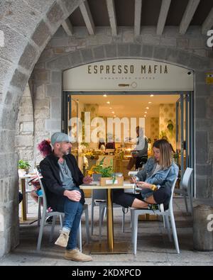 Gérone, Espagne - 21st octobre 2022 : un couple fait une pause et un café à l'extérieur de l'un des nombreux cafés de la vieille ville de Gérone Banque D'Images