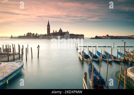 Gondoles floues flottant sur l'eau calme du bassin de San Marco près de l'île avec l'église de San Giorgio Maggiore contre ciel nuageux ensoleillé à Venise, Italie Banque D'Images