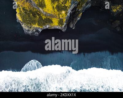 Vue de haut en bas des vagues mousseuse qui atterrissent sur la plage noire de Reynisfjara Banque D'Images