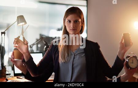 Parfois deux bras juste assez arents. Prise de vue améliorée d'un jeune designer avec quatre bras tenant différents objets tout en se tenant dans son bureau. Banque D'Images