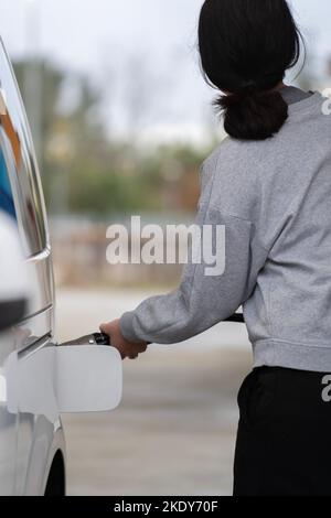 Vue arrière de la femme dans les vêtements de sport ravitaillant la voiture Banque D'Images