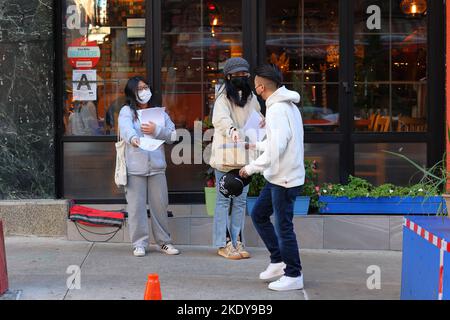 Deux femmes sino-américaines avec endossement multilingue font des dépliants électoraux devant un bureau de vote dans Manhattan Chinatown, New York, 8 novembre 2022 Banque D'Images