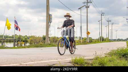 SAMUT PRAKAN, THAÏLANDE, SEP 21 2022, Un senior conduit à vélo sur la route rurale Banque D'Images