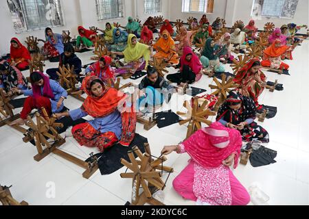 Les travailleurs font tourner le fil de coton pour fabriquer des vêtements de mousseline traditionnels dans un atelier à Narayanganj. Avec ses roues tournants en bois et ses métiers à tisser dessinés à la main, le Bangladesh ressuscite minutieusement un tissu autrefois porté par Marie-Antoinette et Jane Austen, mais longtemps considéré comme perdu à jamais dans l'histoire. -Aller avec 'Bangladesh-Fashion-Muslin'. Sur 8 novembre 2022 à Narayanganj, Dhaka, Bangladesh. Photo de Habibur Rahman/ABACAPRESS.COM Banque D'Images