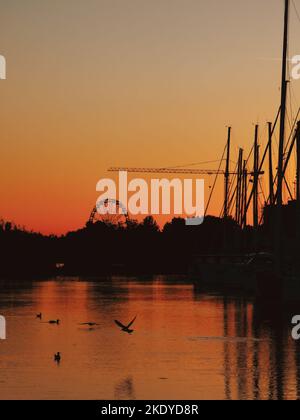 Photo verticale d'un ciel orangé au coucher du soleil sur le lac Balaton avec la roue de Keszthely silhouette Banque D'Images