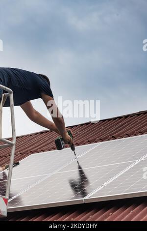 Installation du panneau solaire sur un toit de grange rouge. Banque D'Images