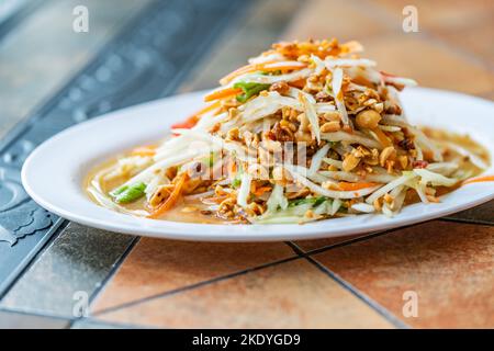 Salade de papaye ou Som Tum Thai, salade de papaye aigre et épicée de Thaïlande, vue latérale, gros plan, lumière chaude naturelle. Banque D'Images