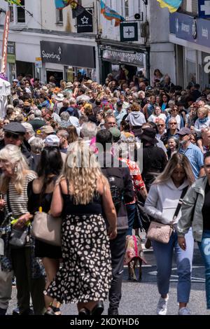 Touristes vacanciers en vacances sur une marche dans un marché bondé Jew Street à Penzance dans Cornwall au Royaume-Uni. Banque D'Images