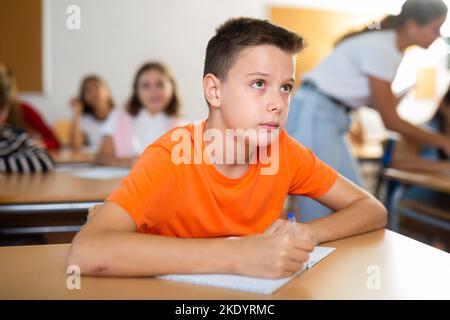 Entre les garçons diligent prenant des notes de la conférence de l'enseignant en classe Banque D'Images