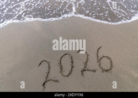 Texte bonne année 2026 sur une plage de sable avec une petite vague. Résumé photo de fond du nouvel an 2023 à venir Banque D'Images