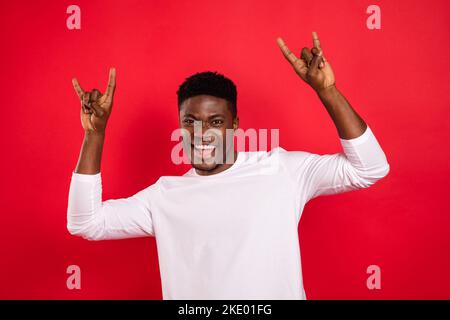 Portrait de la personne positive enfantine deux bras les doigts montrent un symbole de métal lourd isolé sur fond rouge Banque D'Images