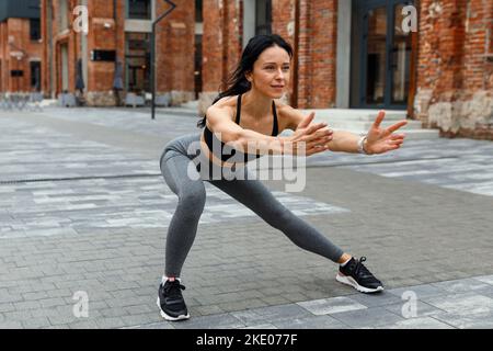 Femme de fitness faisant une fente latérale avec les bras étirés Banque D'Images