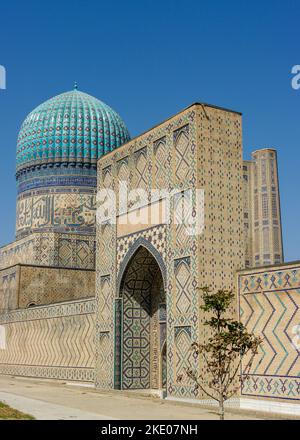 Vue sur la rue de l'ancienne mosquée Bibi Khanum ou Khanym avec dôme en carreaux bleus et porte à Samarkand, classée au patrimoine mondial de l'UNESCO Banque D'Images