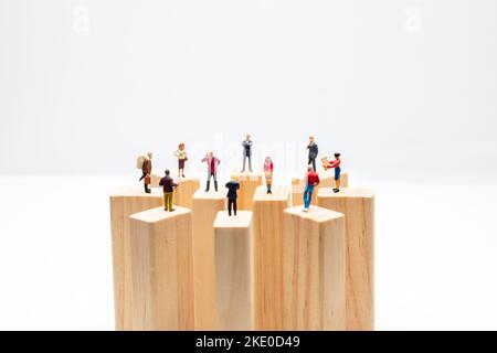 Jouets miniatures sur bloc de bois - distanciation sociale, anti-social ou concept de travail d'équipe. Banque D'Images