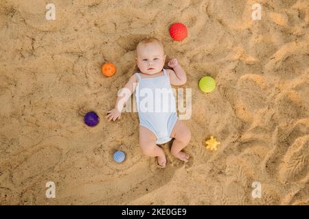 Vue de dessus d'un petit garçon heureux allongé sur une plage de sable Banque D'Images