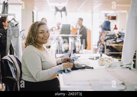 Portrait d'une femme styliste souriante assise à l'établi dans un atelier Banque D'Images