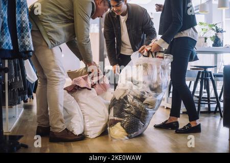 Les créateurs de mode découpant les vêtements recyclés des sacs en plastique à l'atelier Banque D'Images