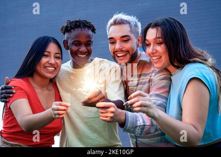 Groupe diversifié d'amis ayant le plaisir de célébrer avec des sparkers - Focus sur le visage asiatique de fille Banque D'Images