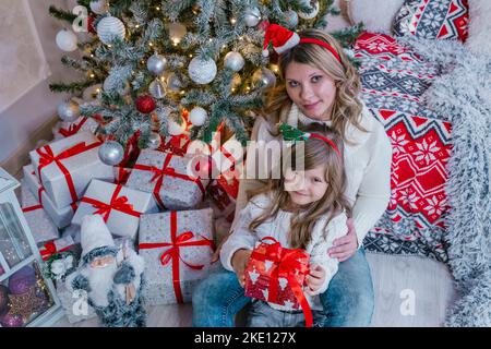 La veille de noël en famille bonne maman et fille ouvrent des cadeaux dans la décoration de noël Banque D'Images