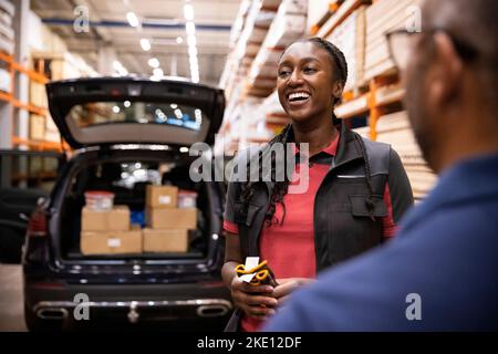 Une bonne vendeuse se tenant avec le client dans l'entrepôt du magasin de matériel Banque D'Images