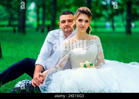 Un couple de jeunes mariés se trouve dans un parc en été sur l'herbe Banque D'Images