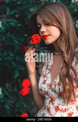 Les filles avec rouge à lèvres regarde les roses Banque D'Images