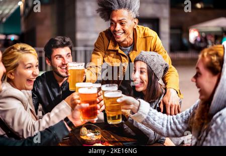 Des amis heureux buvant de la bière dans le jardin du bar de la brasserie à l'extérieur - concept multiracial de style de vie avec des personnes authentiques appréciant le temps ensemble Banque D'Images