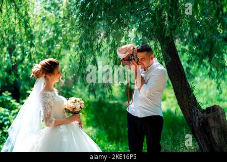 Marié photographiant sa mariée dans le parc Banque D'Images