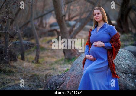 Une femme enceinte dans un foulard rouge est assise près de la rivière Banque D'Images