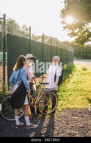 Femmes âgées avec vélo parlant à une amie femelle le jour ensoleillé Banque D'Images