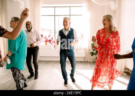 Des hommes et des femmes âgés heureux qui apprécient tout en pratiquant la danse en classe Banque D'Images