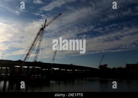 Silhouette de grues de construction travaillant sur l'Arkansas River Bridge, Interstate 30, dans le centre-ville de Little Rock, au lever du soleil. Banque D'Images