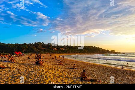 Les gens regardent un magnifique coucher de soleil coloré et doré sur la plage et un panorama sur les grandes vagues dans la nature tropicale de Zicatela P. Banque D'Images