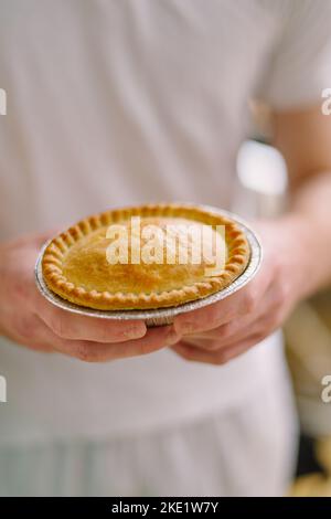 Tarte et pasties à vendre dans une boulangerie, mains tenant une tarte Banque D'Images