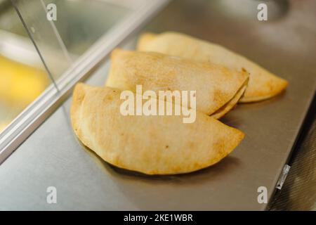Tarte et pasties à vendre dans une boulangerie, mains tenant une tarte Banque D'Images
