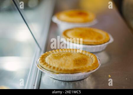 Tarte et pasties à vendre dans une boulangerie, mains tenant une tarte Banque D'Images