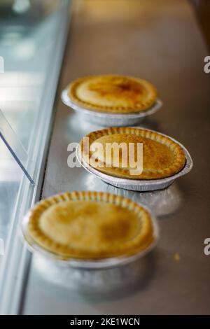 Tarte et pasties à vendre dans une boulangerie, mains tenant une tarte Banque D'Images