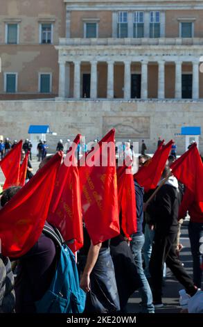 Les manifestants qui détiennent des drapeaux rouges passent par le Parlement grec, qui est gardé par les forces de police, lors d'une manifestation de masse et d'une grève générale. Banque D'Images