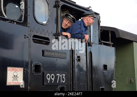 Le conducteur de train et le pompier regardent de la cabine de leur station de vapeur à la voie étroite Lößnitzgrundbahn à Dresde, en Allemagne Banque D'Images