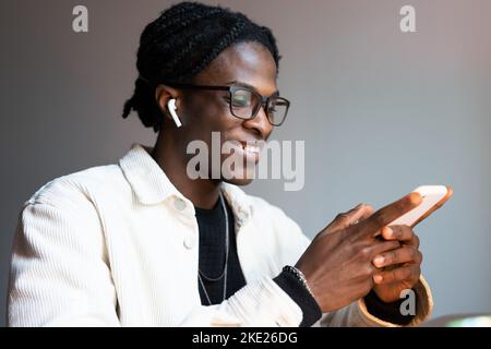 Un homme afro-américain souriant utilise des applications mobiles ou des réseaux sociaux Banque D'Images